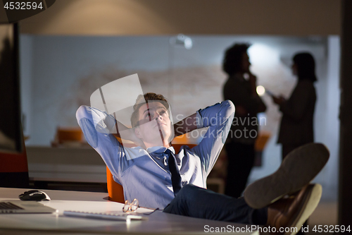 Image of businessman sitting with legs on desk at office