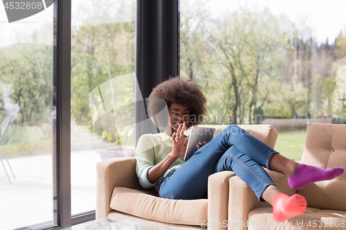 Image of young african american woman at home using digital tablet