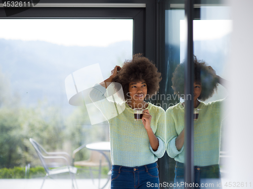 Image of African American woman drinking coffee looking out the window