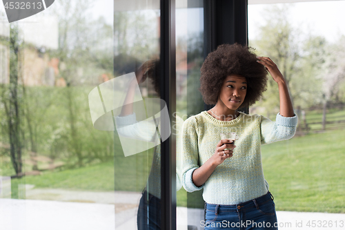 Image of African American woman drinking coffee looking out the window
