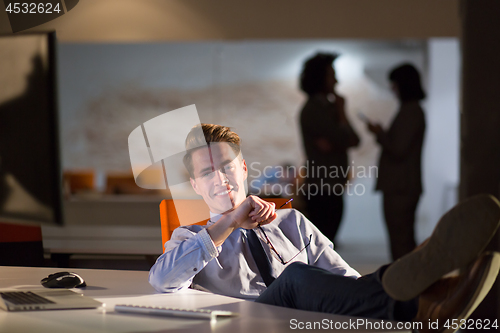 Image of businessman sitting with legs on desk at office