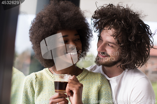 Image of happy multiethnic couple relaxing at modern home indoors