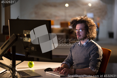 Image of man working on computer in dark office