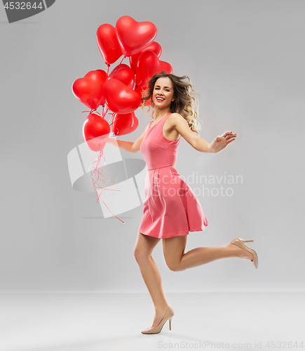 Image of happy young woman with red heart shaped balloons