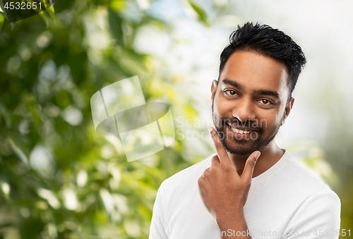 Image of smiling indian man touching his beard