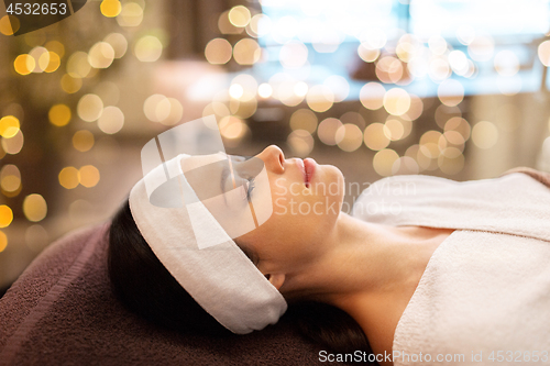 Image of young woman with headband lying in spa parlor