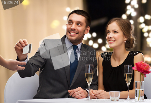 Image of happy couple at restaurant paying by credit card