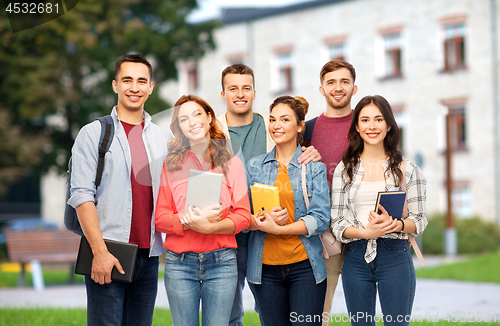 Image of group of smiling students with books over campus