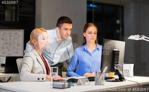 Image of business team with computer working late at office