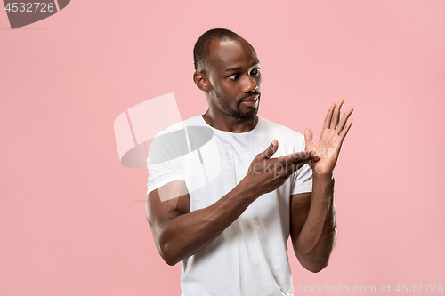 Image of Beautiful male half-length portrait isolated on pink studio backgroud. The young emotional surprised man