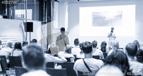 Image of Businessman in audience standing and asking question to speeker at business conference.