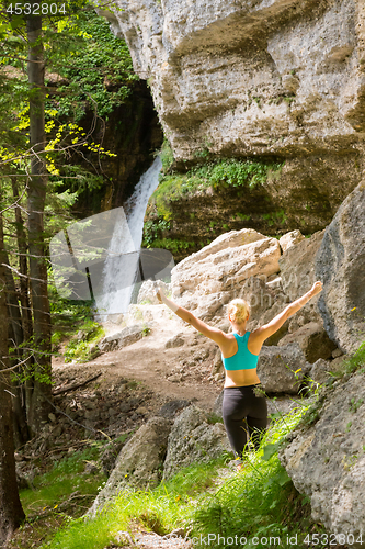 Image of Active woman raising arms inhaling fresh air, feeling relaxed in nature.