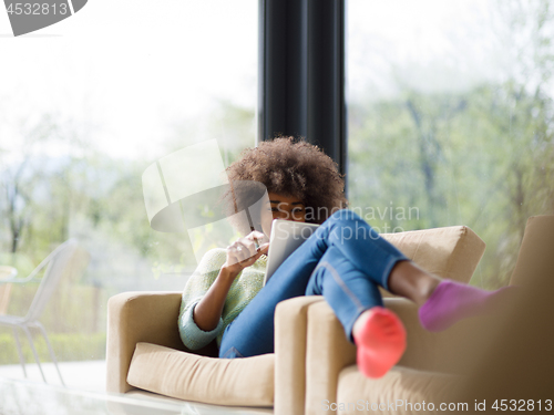 Image of young african american woman at home using digital tablet