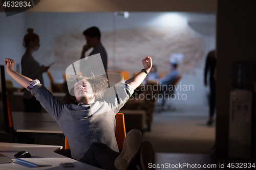 Image of businessman sitting with legs on desk at office