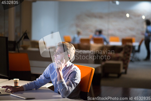 Image of man using mobile phone in dark office