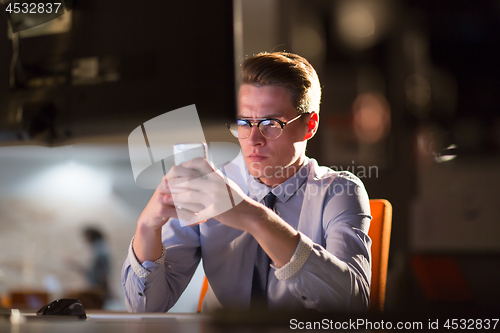 Image of man using mobile phone in dark office