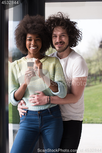 Image of happy multiethnic couple relaxing at modern home indoors
