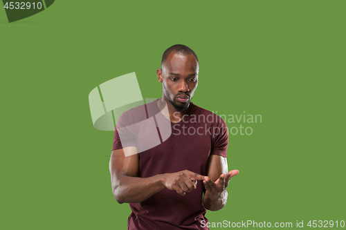 Image of Beautiful male half-length portrait isolated on green studio backgroud. The young emotional surprised man