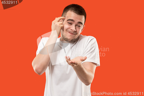 Image of Beautiful male half-length portrait isolated on orange studio backgroud. The young emotional surprised man