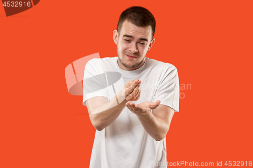 Image of Beautiful male half-length portrait isolated on orange studio backgroud. The young emotional surprised man