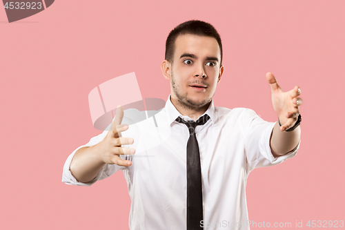 Image of Beautiful male half-length portrait isolated on pink studio backgroud. The young emotional surprised man