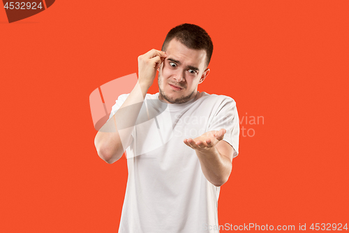 Image of Beautiful male half-length portrait isolated on orange studio backgroud. The young emotional surprised man