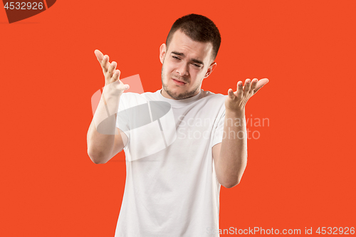 Image of Beautiful male half-length portrait isolated on orange studio backgroud. The young emotional surprised man