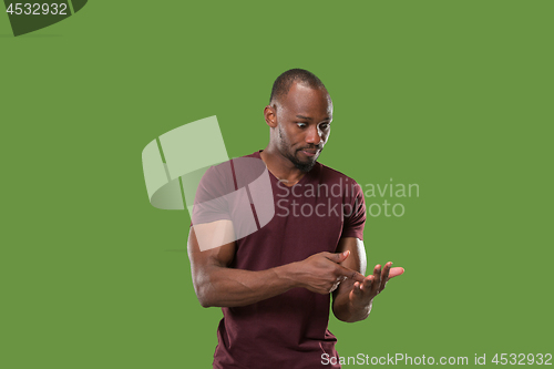 Image of Beautiful male half-length portrait isolated on green studio backgroud. The young emotional surprised man