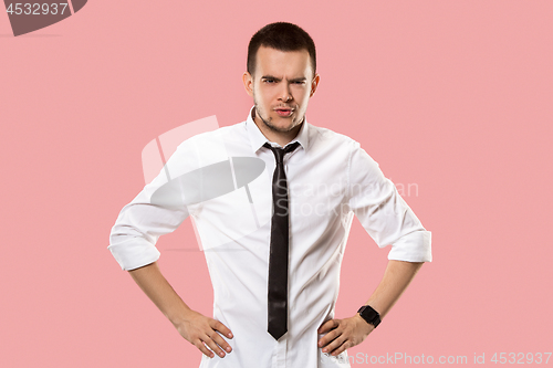 Image of The serious businessman standing and looking at camera against pink background.