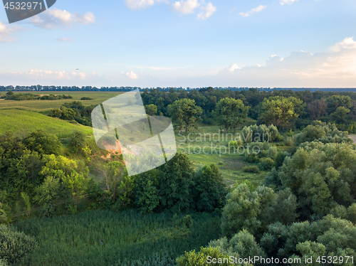 Image of Aerial view from the drone of a natural landscape with greenery, forest, field, ravine on a background of a cloudy sky.