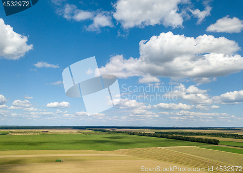 Image of Summer landscape with agricultural fields, harvesting on a backgground of the blue sky and white clouds in a sunny day. View from drone.