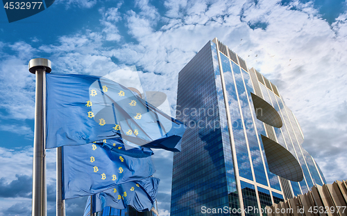 Image of Blue flag of the European Union with bitcoin icons and a modern building in the form of a symbol of bitcoin against a sky with white clouds