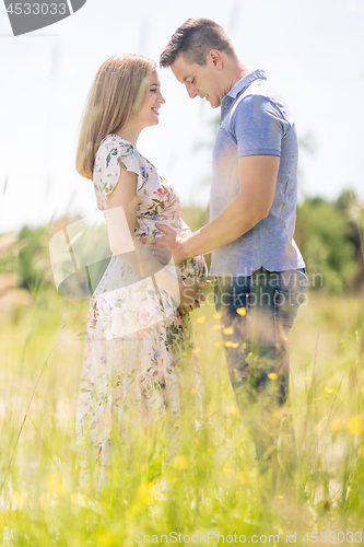 Image of Young happy pregnant couple hugging in nature.