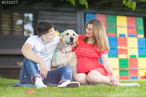 Image of A Young couple expecting baby with their Golden retriever dog