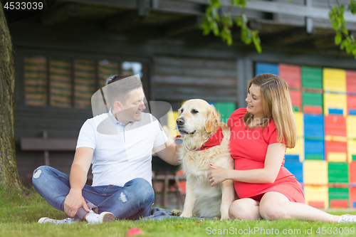 Image of A Young couple expecting baby with their Golden retriever dog