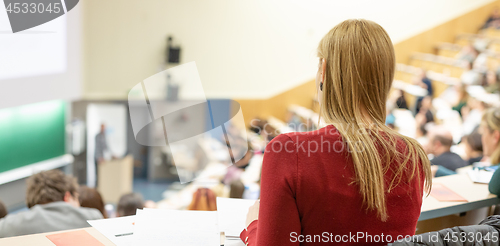 Image of Audience in the lecture hall. Female student making notes.