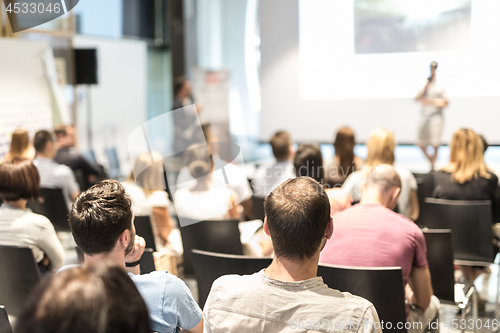 Image of Businessman in audience standing and asking question to speeker at business conference.