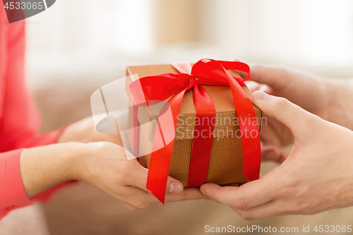 Image of close up of male and female hands with gift box