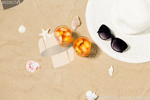 Image of cocktails, sun hat and sunglasses on beach sand