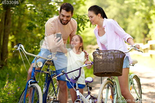 Image of family with smartphone and bicycles in summer park