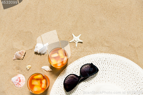 Image of cocktails, sun hat and sunglasses on beach sand