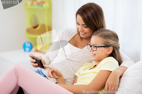 Image of happy mother and daughter with smartphone at home