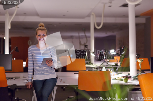 Image of woman working on digital tablet in night office