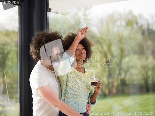Image of happy multiethnic couple relaxing at modern home indoors
