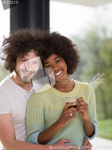 Image of happy multiethnic couple relaxing at modern home indoors