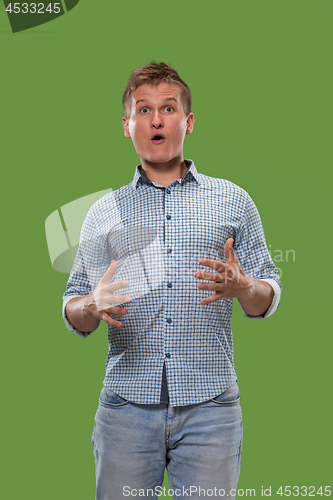 Image of The young attractive man looking suprised isolated on green