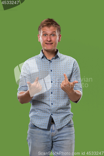 Image of The young attractive man looking suprised isolated on green