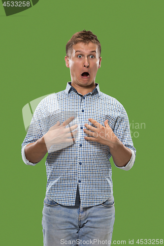 Image of The young attractive man looking suprised isolated on green