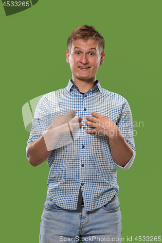 Image of The young attractive man looking suprised isolated on green