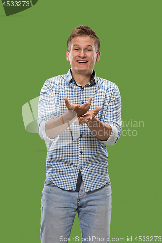 Image of Beautiful male half-length portrait isolated on green studio backgroud. The young emotional surprised man